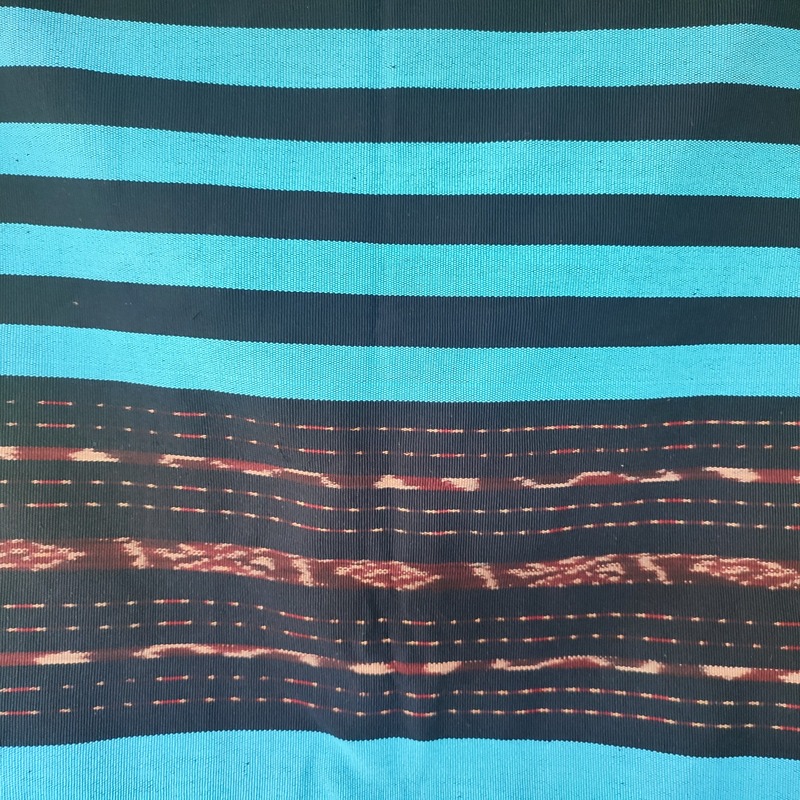 Tuka Dulan: Jejak Leluhur, Jalan Pulang
Motif ini didominasi warna hitam, melambangkan kedalaman sejarah dan kekuatan yang tak tergoyahkan.
Tenun ini dibuat oleh perempuan yang tidak pernah menyerah, melambangkan keheningan, keteguhan, dan keteduhan.
Pewarna hitam alami berasal dari daun tarum yang diproses secara perlahan, tanpa mesin atau racun.


