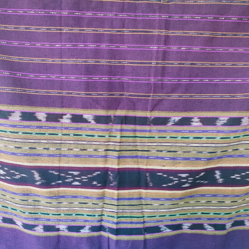 Motif Kumha: Ombak yang Tak Pernah Diam
Benang-benang kapas lokal diwarnai secara alami dengan kunyit, daun mangga, dan kulit pohon kuning oleh para penenun muda dan ibu-ibu.
Setiap tetes warna berasal dari alam, tanpa racun atau limbah.
Kain ini adalah perayaan hidup yang terus tumbuh di tengah keterbatasan. Warna kuningnya melambangkan senyum hangat seorang ibu, cahaya pagi, rasa syukur dalam diam, dan kekuatan yang menghidupi.
Kain ini digunakan pada acara adat, upacara perkawinan, Misa-misa besar, dan sebagai pelengkap mas kawin.
